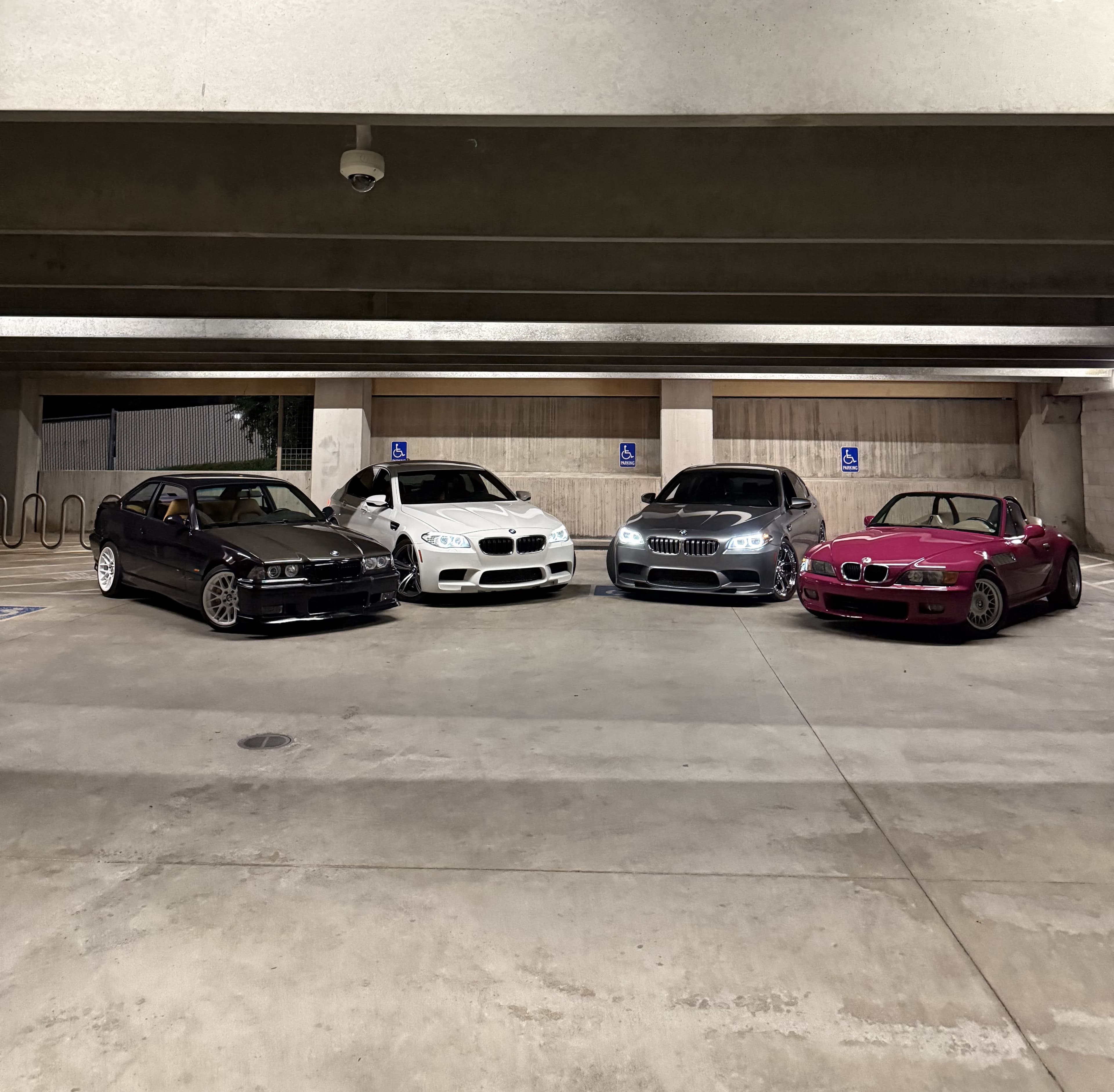 Four BMWs lined up in a parking garage, including the Z3 wrapped in RubyStar.